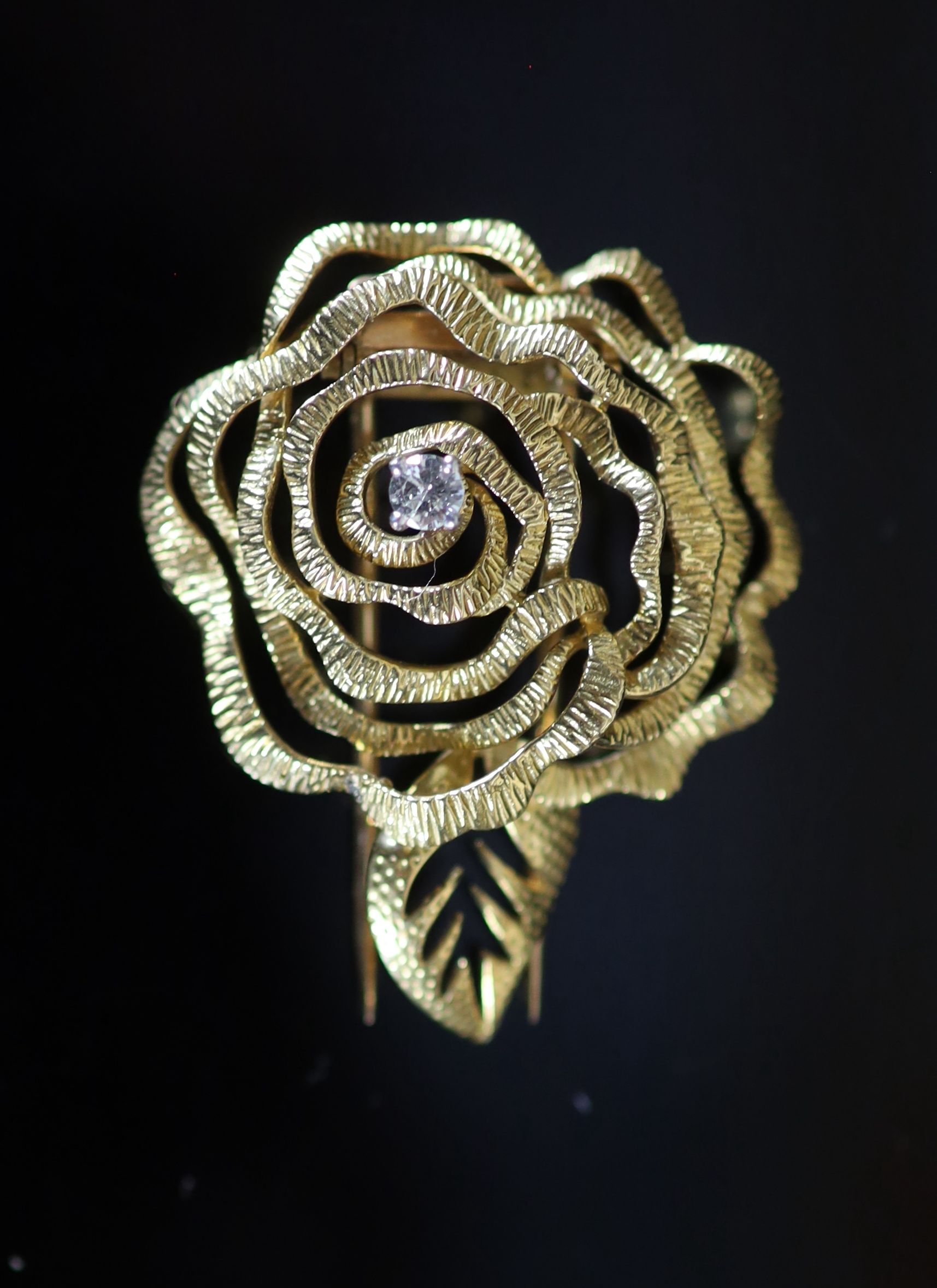 A 1980's French Cartier textured 18ct gold and diamond set 'open rose' clip brooch